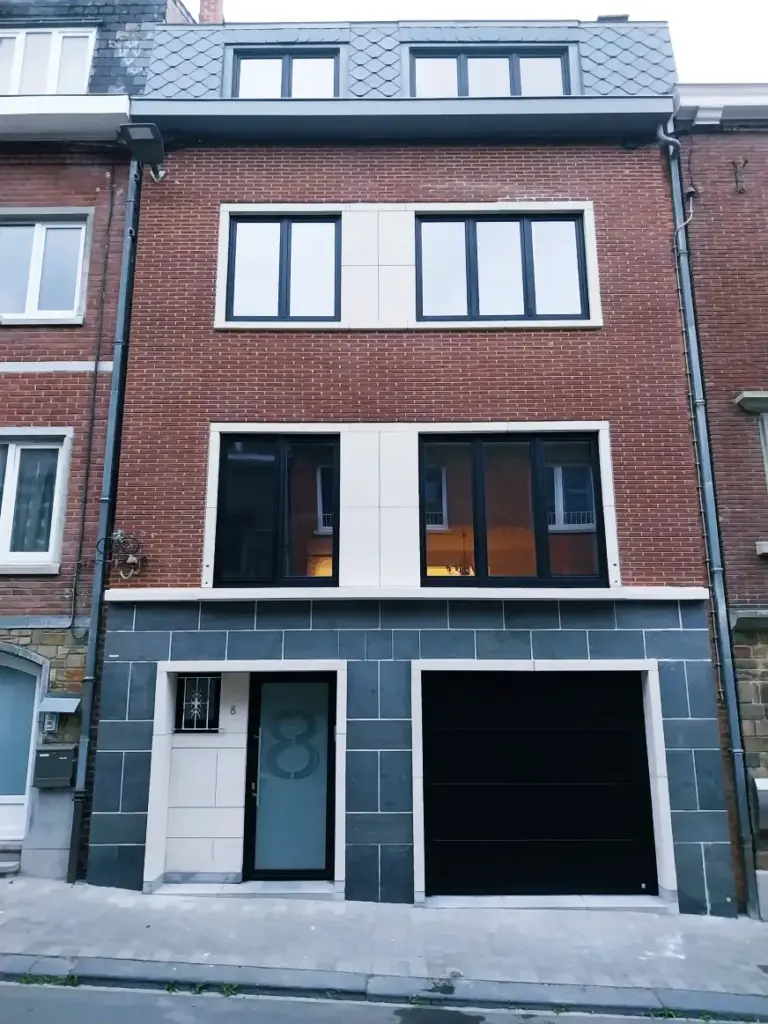 Porte de garage sectionnelle noire et porte d'entrée assortie sur maison en briques