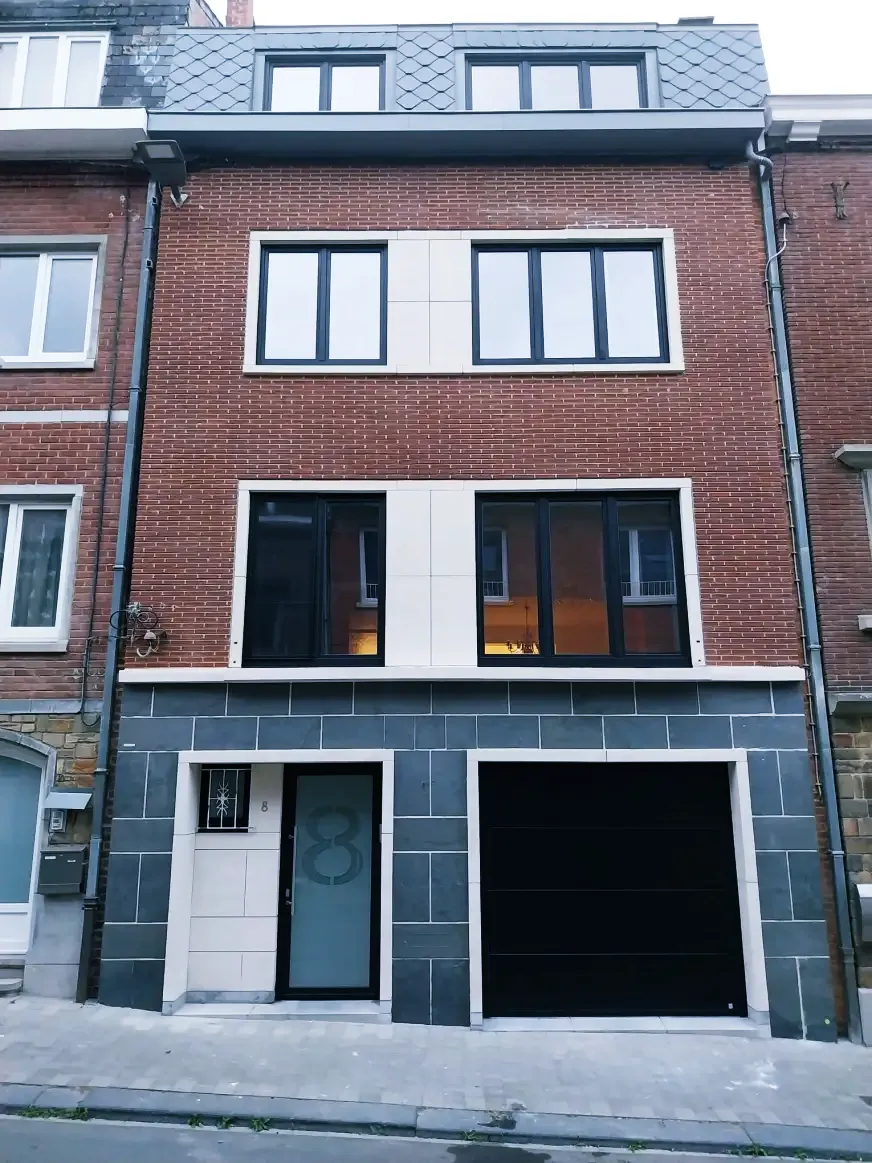 Porte de garage sectionnelle noire et porte d'entrée assortie sur maison en briques