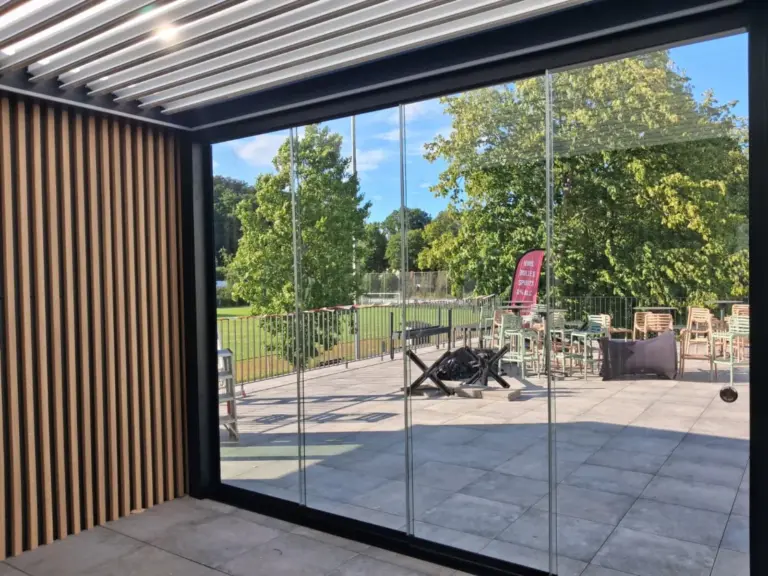Vue depuis l'intérieur de la véranda bioclimatique sur la terrasse du club