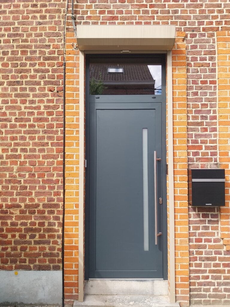 Porte d'entrée gris ardoise avec vitrage vertical étroit, imposte et longue poignée barre inox