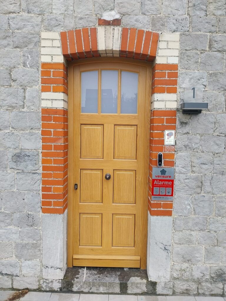Porte d'entrée en bois ton chêne à six panneaux moulurés et imposte vitrée cintrée